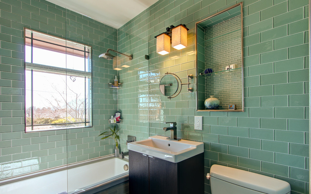 Immagine di una stanza da bagno tradizionale con lavabo a consolle, vasca ad alcova, vasca/doccia, piastrelle verdi e piastrelle di vetro