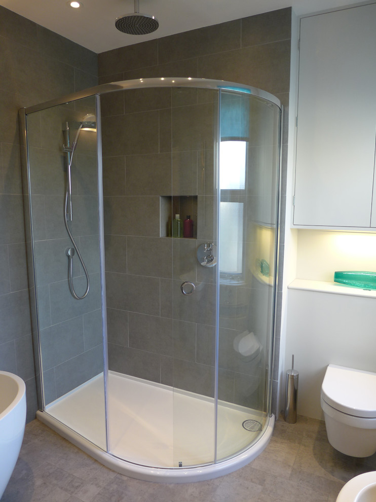 Photo of a medium sized contemporary family bathroom in Other with flat-panel cabinets, grey cabinets, wooden worktops, a corner shower, a wall mounted toilet, grey tiles, porcelain tiles, grey walls and lino flooring.
