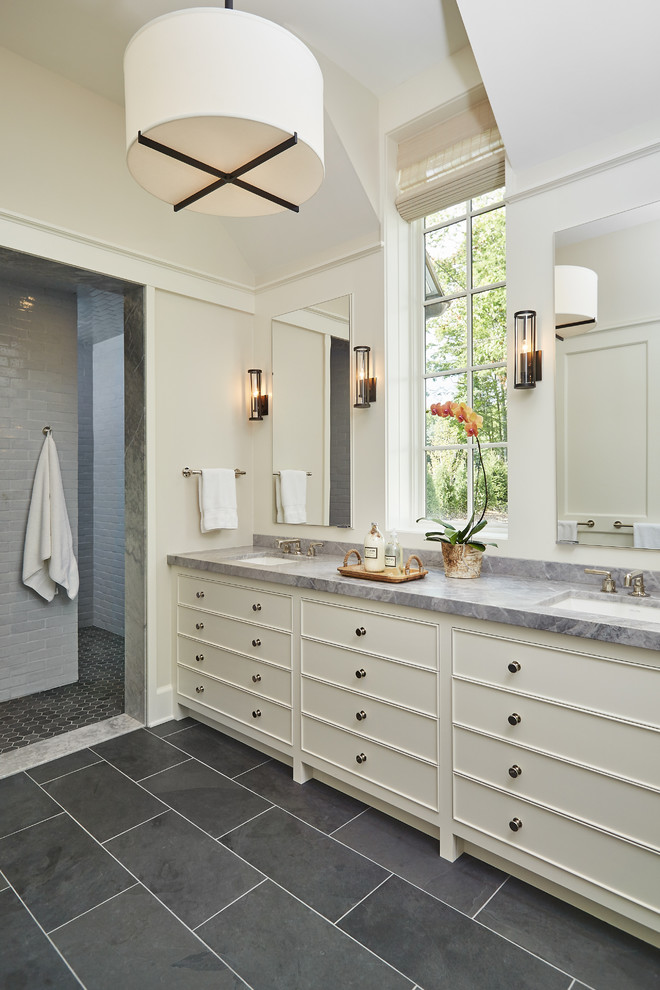 Modelo de cuarto de baño clásico renovado con baldosas y/o azulejos grises, paredes beige, lavabo bajoencimera, puertas de armario blancas y ducha abierta