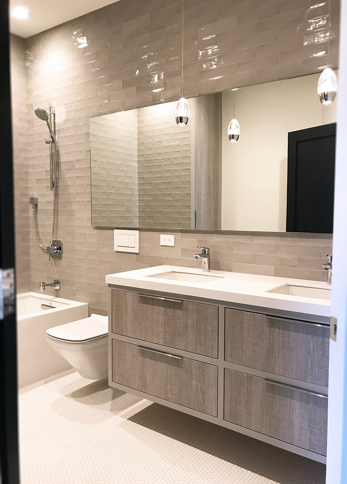 Medium sized contemporary family bathroom in Chicago with flat-panel cabinets, distressed cabinets, an alcove bath, a shower/bath combination, a wall mounted toilet, grey tiles, porcelain tiles, grey walls, pebble tile flooring, a submerged sink, engineered stone worktops, white floors and an open shower.