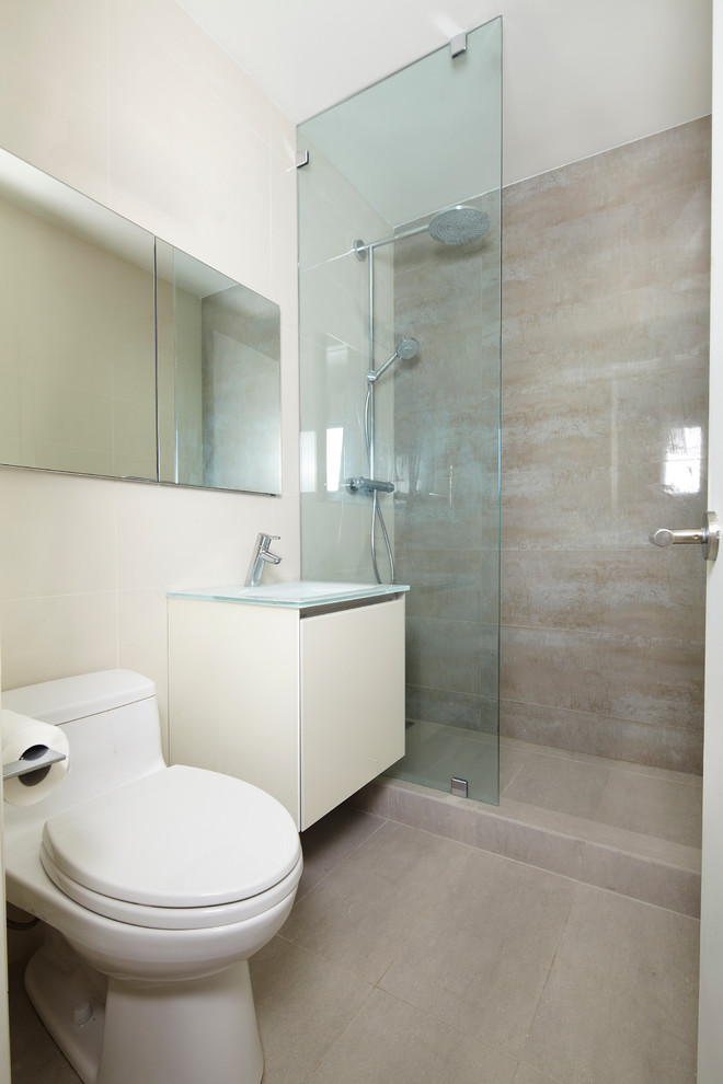 Immagine di una piccola stanza da bagno design con lavabo integrato, ante lisce, ante bianche, top in vetro, doccia aperta, WC monopezzo, piastrelle grigie, piastrelle in gres porcellanato, pareti beige e pavimento in gres porcellanato