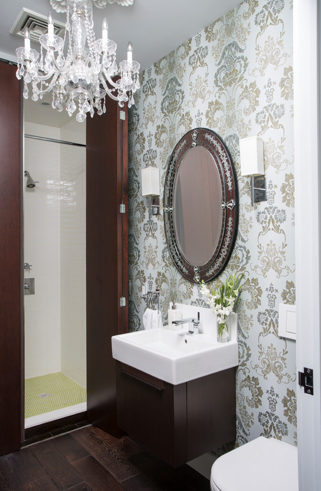Diseño de cuarto de baño ecléctico pequeño con armarios con paneles lisos, puertas de armario de madera en tonos medios, sanitario de pared, paredes multicolor, suelo de madera oscura, lavabo integrado y suelo marrón