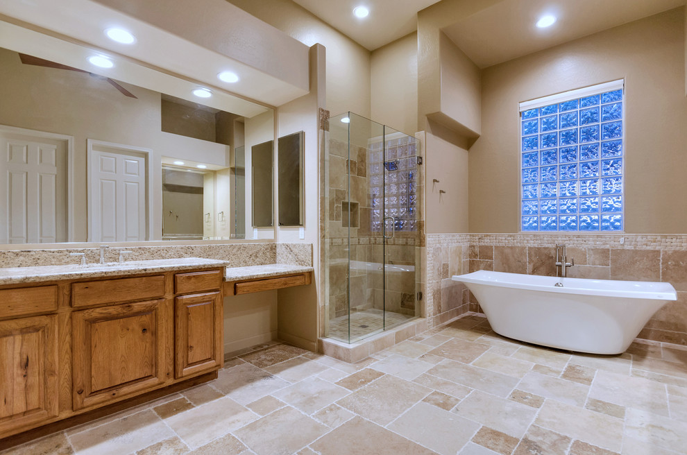 Klassisk inredning av ett stort en-suite badrum, med luckor med upphöjd panel, skåp i mellenmörkt trä, ett fristående badkar, en hörndusch, brun kakel, travertinkakel, bruna väggar, travertin golv, granitbänkskiva, brunt golv, dusch med gångjärnsdörr och ett undermonterad handfat