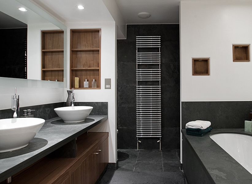 Стильный дизайн: большая главная ванная комната в современном стиле с плоскими фасадами, темными деревянными фасадами, полновстраиваемой ванной, белой плиткой, белыми стенами, полом из сланца, настольной раковиной, столешницей из талькохлорита и черным полом - последний тренд