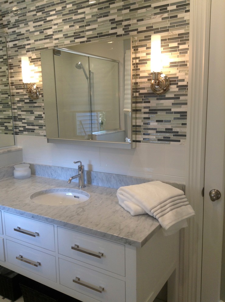 Ejemplo de cuarto de baño actual con lavabo bajoencimera y baldosas y/o azulejos de vidrio