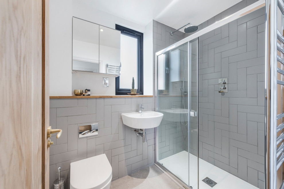 Photo of a medium sized contemporary shower room bathroom in London with a corner shower, a wall mounted toilet, grey tiles, porcelain flooring, a wall-mounted sink, grey floors, a sliding door and a single sink.