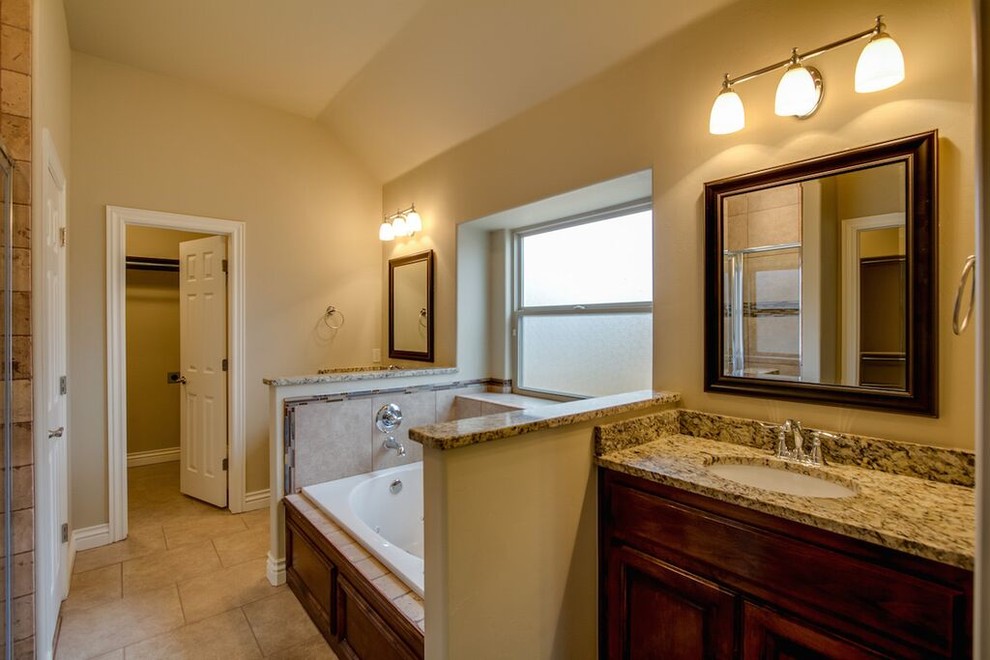 Cette image montre une grande salle de bain principale traditionnelle avec un plan de toilette en granite.