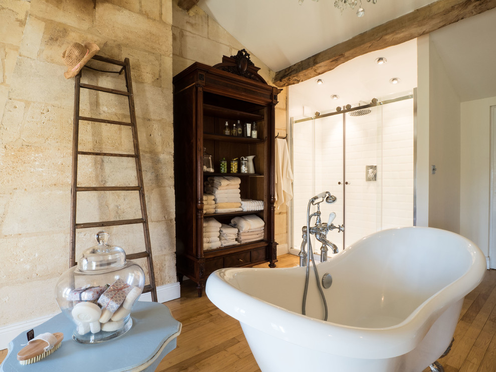 Идея дизайна: большая ванная комната в стиле кантри с ванной на ножках, душем в нише, паркетным полом среднего тона, бежевыми стенами, душем с раздвижными дверями, белой плиткой, плиткой кабанчик и коричневым полом
