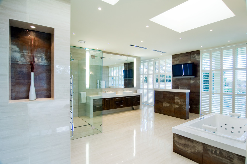 Modern inredning av ett en-suite badrum, med ett fristående handfat, släta luckor, skåp i mörkt trä, ett platsbyggt badkar, en kantlös dusch, beige väggar och brun kakel