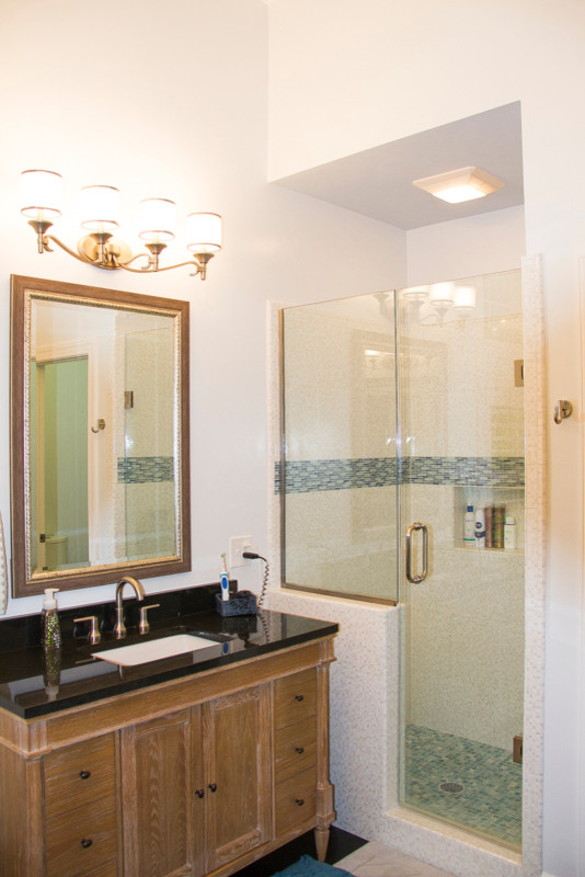 Ejemplo de cuarto de baño principal tradicional renovado de tamaño medio con puertas de armario de madera oscura, ducha empotrada, baldosas y/o azulejos de piedra, paredes beige y lavabo bajoencimera
