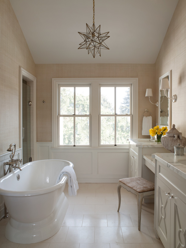 Aménagement d'une salle de bain classique avec un lavabo encastré, un placard avec porte à panneau encastré, des portes de placard blanches, une baignoire indépendante et un mur beige.