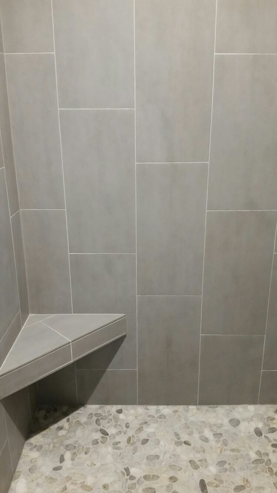 Идея дизайна: главная ванная комната среднего размера в современном стиле с угловым душем, бежевой плиткой, каменной плиткой, серыми стенами и полом из галечной плитки
