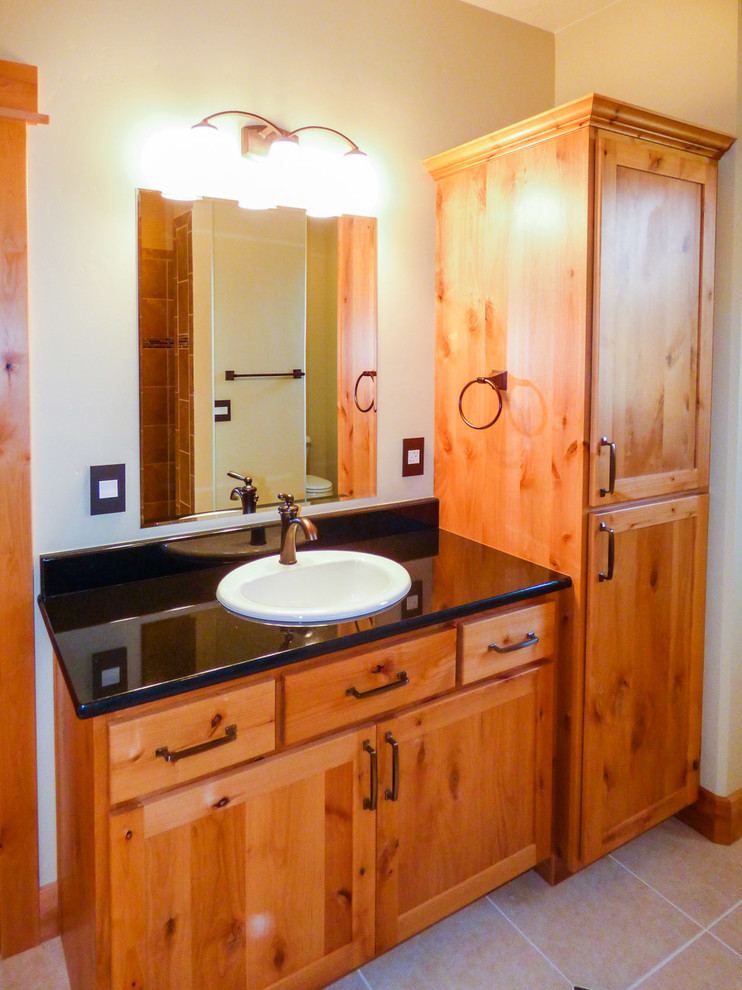 Imagen de cuarto de baño principal de estilo americano de tamaño medio con lavabo encastrado, armarios estilo shaker, puertas de armario de madera clara, encimera de granito y suelo de pizarra