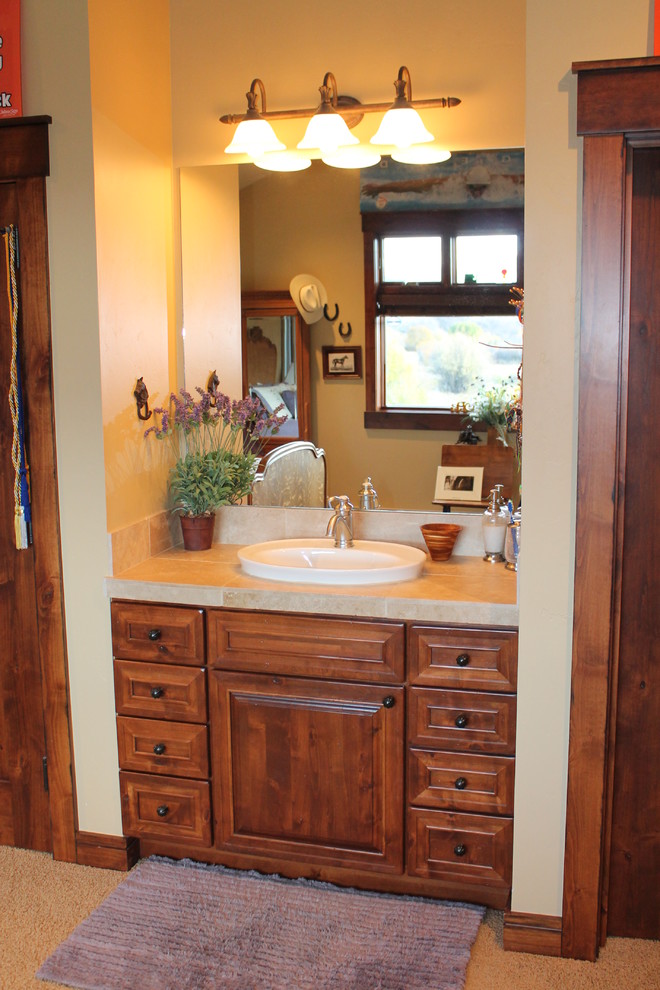 Foto di una stanza da bagno tradizionale con ante con bugna sagomata, ante in legno scuro e top piastrellato