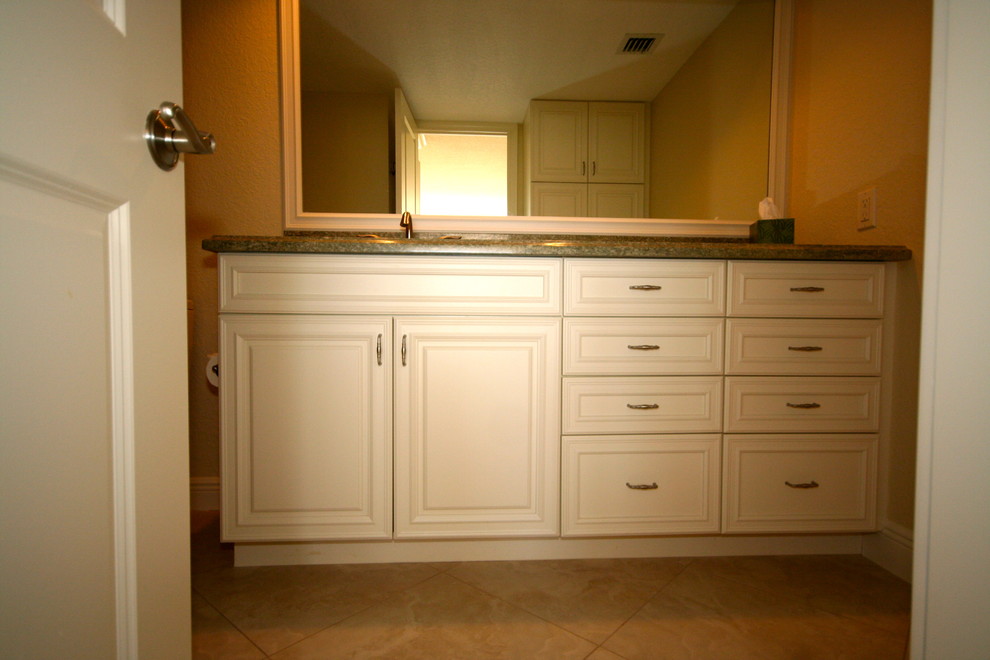 Modelo de cuarto de baño clásico de tamaño medio con armarios con paneles con relieve, puertas de armario blancas, paredes beige, suelo de baldosas de cerámica, aseo y ducha y encimera de granito