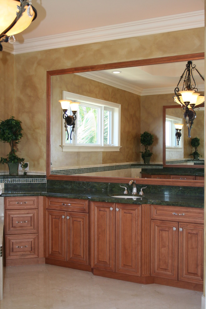 Réalisation d'une grande salle de bain principale tradition en bois brun avec un placard avec porte à panneau surélevé, un carrelage vert, un mur beige, un sol en marbre, un lavabo encastré, un plan de toilette en granite et un plan de toilette vert.