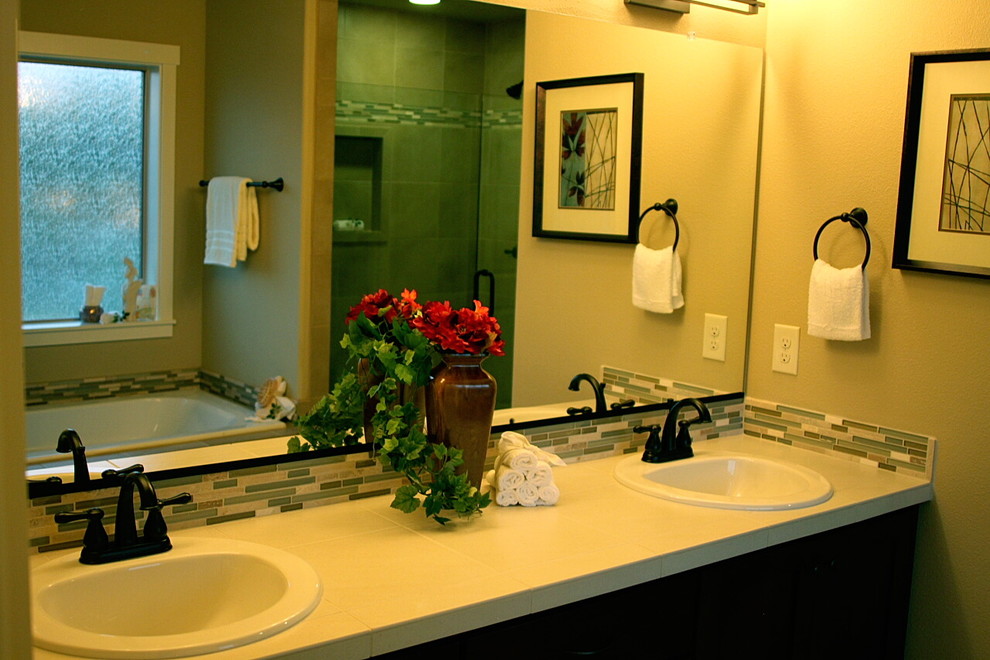 Cette photo montre une salle de bain chic en bois foncé avec un placard avec porte à panneau encastré, un carrelage multicolore, un carrelage en pâte de verre, un mur beige, un lavabo posé, un plan de toilette en carrelage et un plan de toilette beige.