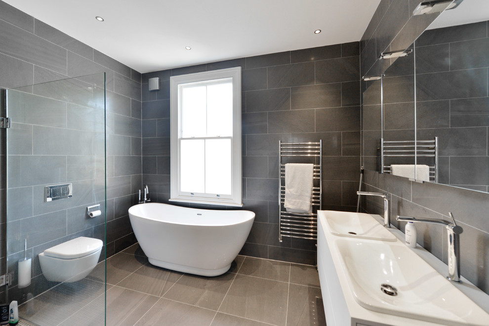 Design ideas for a medium sized modern family bathroom in London with flat-panel cabinets, dark wood cabinets, a freestanding bath, a walk-in shower, a one-piece toilet, black tiles, ceramic tiles, black walls, ceramic flooring, a built-in sink, tiled worktops, black floors and an open shower.