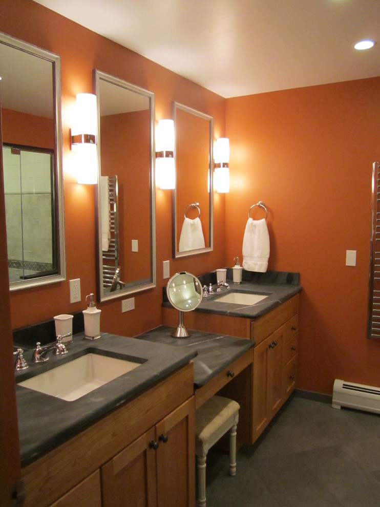 Cette photo montre une salle de bain principale chic en bois brun de taille moyenne avec un lavabo encastré, un placard à porte shaker, un plan de toilette en stéatite, un mur orange et un sol en carrelage de porcelaine.