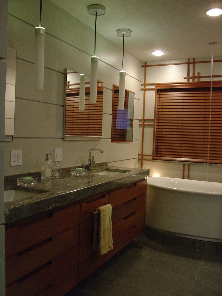 Photo of a large contemporary bathroom in Dallas with a submerged sink, freestanding cabinets, dark wood cabinets, granite worktops, a freestanding bath, a built-in shower, a wall mounted toilet, porcelain tiles, grey walls and porcelain flooring.
