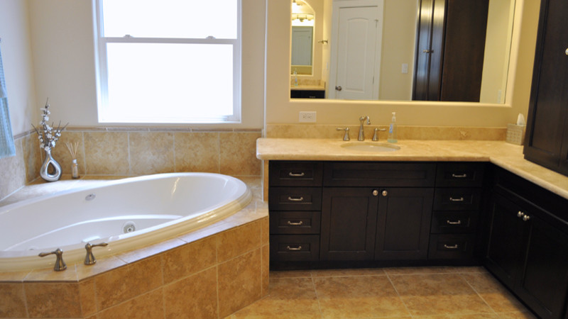Ejemplo de cuarto de baño clásico renovado con lavabo bajoencimera, armarios tipo mueble, puertas de armario de madera en tonos medios, bañera encastrada y baldosas y/o azulejos beige
