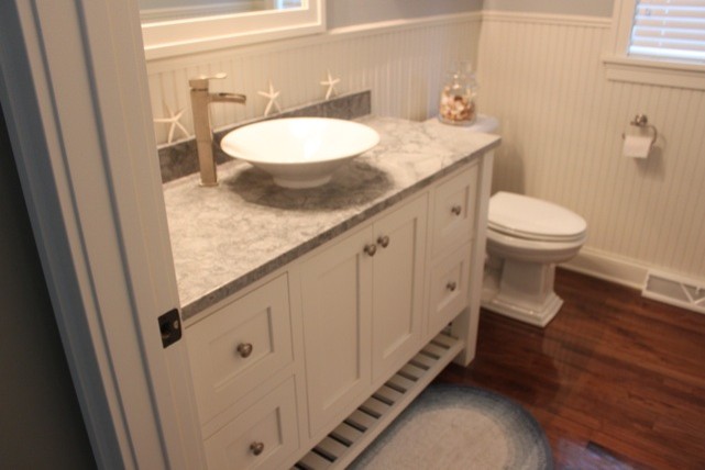 Ejemplo de cuarto de baño clásico con lavabo sobreencimera, armarios estilo shaker, puertas de armario blancas, sanitario de una pieza, paredes amarillas y suelo de madera en tonos medios