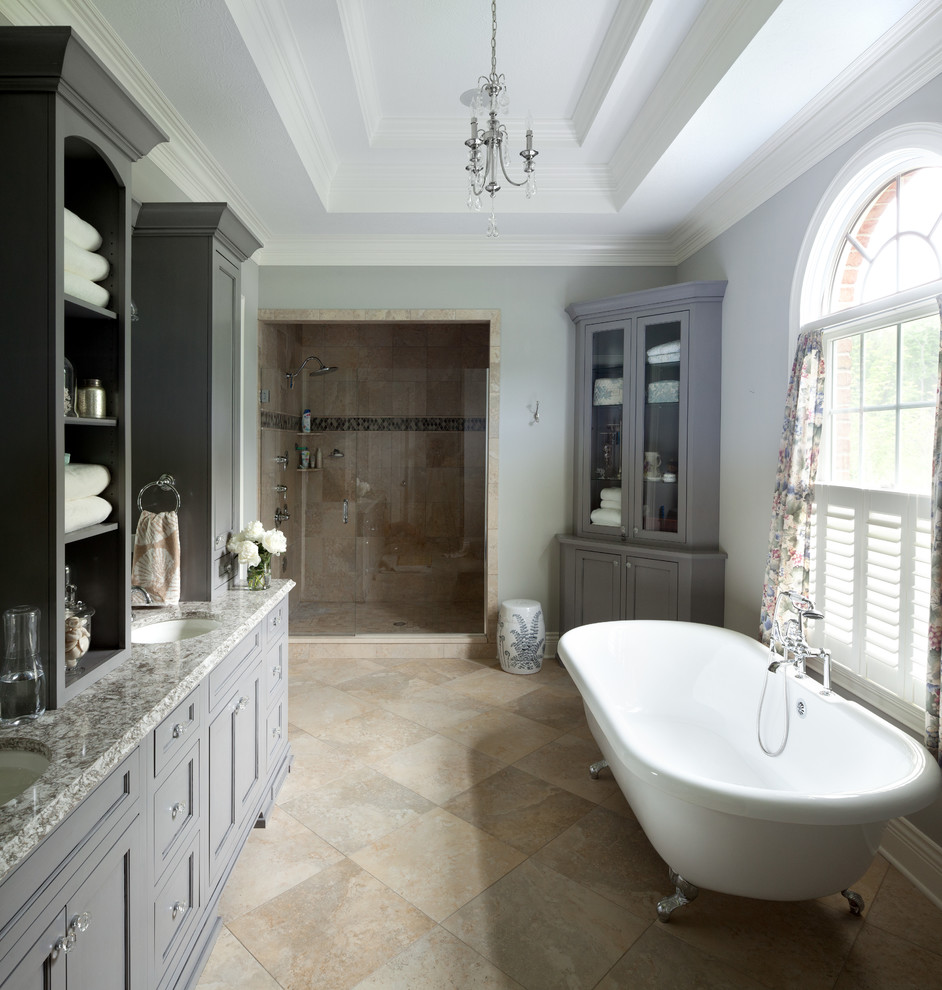 Exemple d'une douche en alcôve chic avec un lavabo encastré, un placard avec porte à panneau encastré, des portes de placard grises, une baignoire sur pieds, un carrelage beige, un mur gris et un plan de toilette gris.
