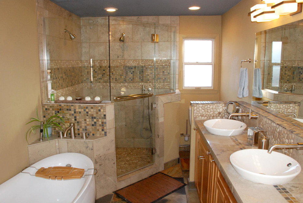 Medium sized classic ensuite bathroom in Portland with recessed-panel cabinets, light wood cabinets, a freestanding bath, a corner shower, a one-piece toilet, pebble tiles, yellow walls, a vessel sink and a hinged door.