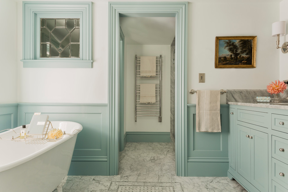 Aménagement d'une douche en alcôve principale victorienne avec un lavabo encastré, un placard avec porte à panneau encastré, des portes de placard bleues, un plan de toilette en marbre, une baignoire sur pieds, un carrelage gris, un carrelage de pierre, un mur blanc et un sol en marbre.