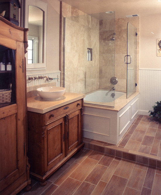 Inspiration pour une salle de bain principale traditionnelle en bois brun avec une vasque, un placard à porte affleurante, un plan de toilette en calcaire, une baignoire posée, un combiné douche/baignoire, un mur beige et parquet clair.