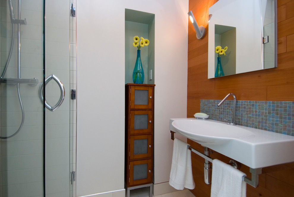 This is an example of a contemporary ensuite bathroom in San Francisco with a walk-in shower, blue tiles, porcelain tiles, white walls, ceramic flooring, a wall-mounted sink and solid surface worktops.