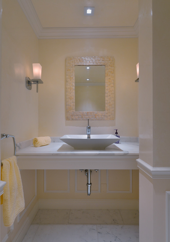 ニューヨークにある小さなトランジショナルスタイルのおしゃれな浴室 (ベッセル式洗面器、大理石の洗面台、一体型トイレ	、黄色い壁、大理石の床) の写真