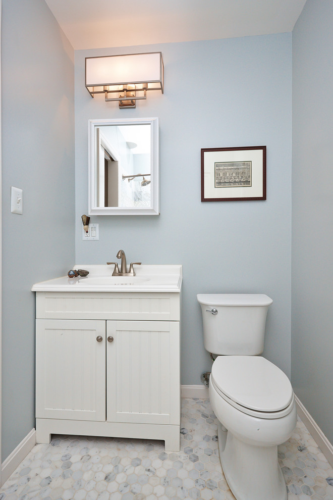 Cette photo montre une salle d'eau tendance de taille moyenne avec un lavabo intégré, un placard à porte affleurante, des portes de placard blanches, WC à poser, un carrelage blanc, un mur bleu, un sol en carrelage de terre cuite, un plan de toilette en surface solide et une douche d'angle.