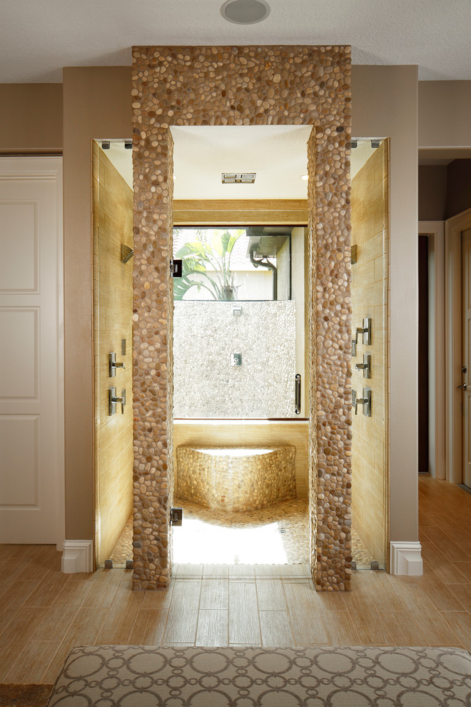 Traditional bathroom in Orlando with a built-in shower, beige tiles, pebble tiles, beige walls, raised-panel cabinets, medium wood cabinets, a built-in bath, porcelain flooring, a vessel sink, soapstone worktops, beige floors and an open shower.
