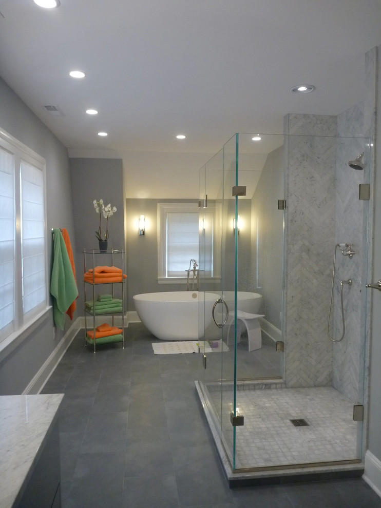 Cette photo montre une grande salle de bain principale tendance avec un lavabo encastré, un placard à porte plane, des portes de placard grises, un plan de toilette en marbre, une baignoire indépendante, une douche ouverte, un carrelage gris, un mur gris et un sol en carrelage de porcelaine.