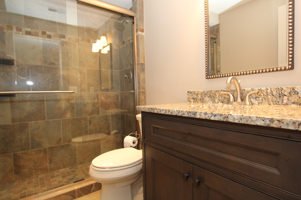 Inredning av ett klassiskt mellanstort badrum med dusch, med ett undermonterad handfat, granitbänkskiva, en dubbeldusch, en toalettstol med hel cisternkåpa, beige kakel, keramikplattor, svarta väggar och klinkergolv i keramik
