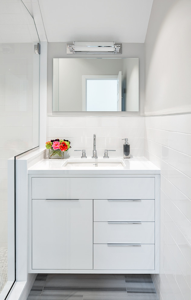 This is an example of a small contemporary shower room bathroom in New York with a submerged sink, flat-panel cabinets, white cabinets, white tiles and grey walls.