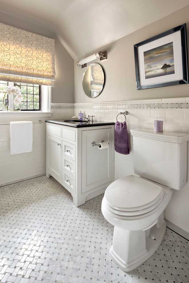 This is an example of a contemporary bathroom in New York with a submerged sink, white cabinets, granite worktops, a two-piece toilet, white tiles, metro tiles, recessed-panel cabinets and grey floors.
