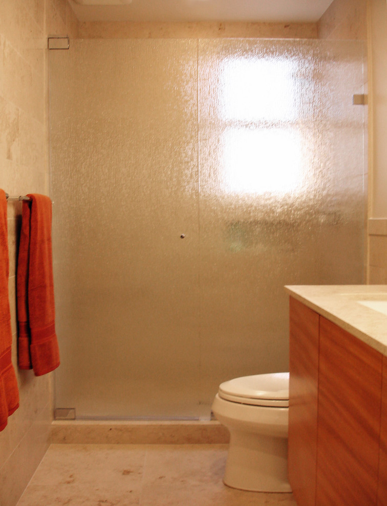 Esempio di una stanza da bagno con doccia minimal di medie dimensioni con lavabo sottopiano, ante lisce, ante in legno scuro, top in pietra calcarea, WC monopezzo, piastrelle beige, piastrelle in pietra, pareti beige, pavimento in pietra calcarea e doccia aperta