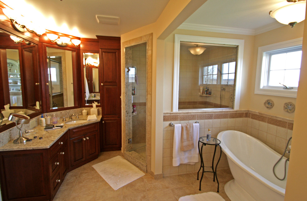 Bild på ett stort maritimt en-suite badrum, med ett undermonterad handfat, luckor med upphöjd panel, skåp i mörkt trä, granitbänkskiva, ett fristående badkar, en dusch i en alkov, beige kakel, keramikplattor, beige väggar och travertin golv