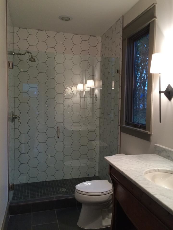 Klassisk inredning av ett litet badrum med dusch, med öppna hyllor, bruna skåp, en dusch i en alkov, porslinskakel, vita väggar, klinkergolv i porslin, ett undermonterad handfat, marmorbänkskiva, grått golv och dusch med gångjärnsdörr
