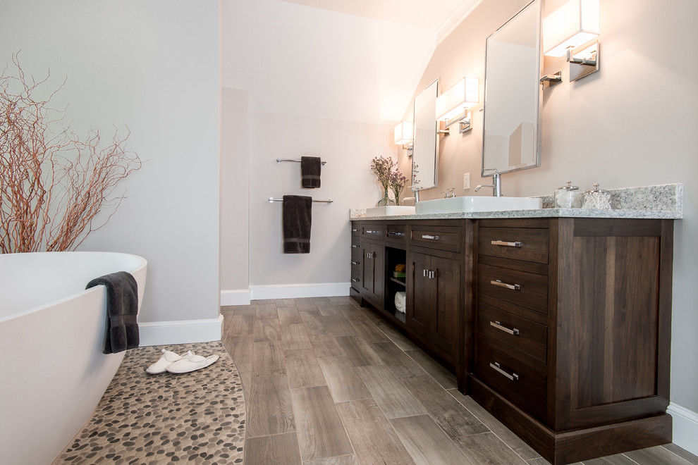 Bathroom - large transitional master gray tile and ceramic tile pebble tile floor and gray floor bathroom idea in Bridgeport with shaker cabinets, dark wood cabinets, a two-piece toilet, gray walls, a vessel sink, quartz countertops, a hinged shower door and white countertops