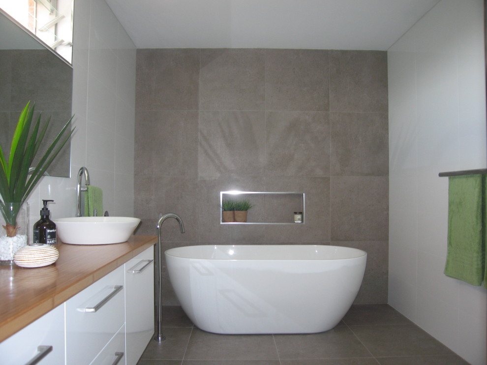 Idéer för stora funkis en-suite badrum, med vita skåp, ett fristående badkar, beige kakel, keramikplattor, vita väggar, klinkergolv i porslin, ett fristående handfat och träbänkskiva