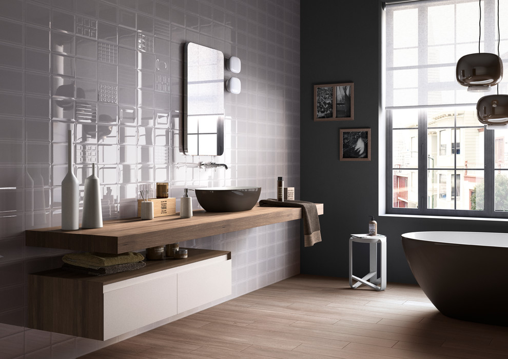 Imagen de cuarto de baño contemporáneo con lavabo sobreencimera, bañera exenta, paredes grises y suelo de madera en tonos medios