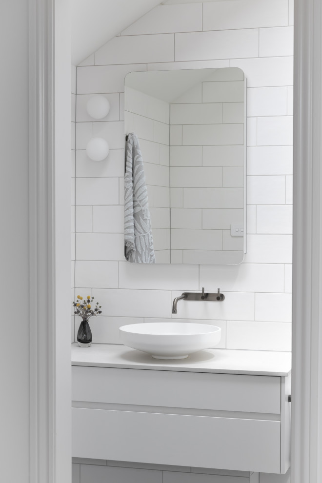 Immagine di una stanza da bagno minimal con ante lisce, ante bianche, piastrelle bianche, lavabo a bacinella, top bianco, un lavabo, mobile bagno sospeso e soffitto a volta