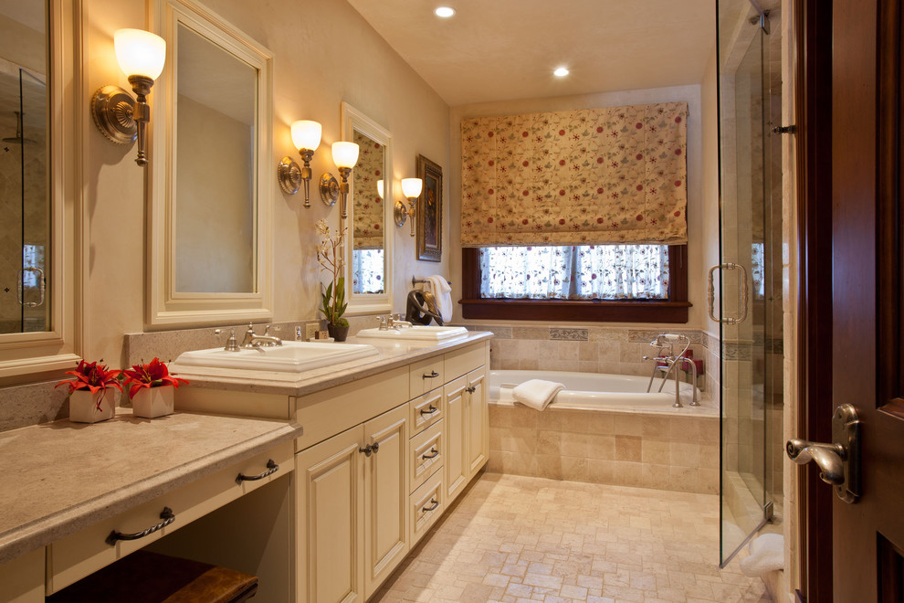 Cette photo montre une douche en alcôve chic avec un lavabo posé, un placard avec porte à panneau surélevé, des portes de placard beiges, une baignoire posée et un carrelage beige.