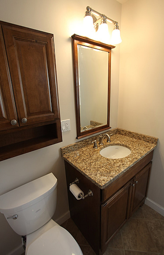Foto di una stanza da bagno tradizionale di medie dimensioni con ante con bugna sagomata, ante in legno bruno, WC a due pezzi, pareti beige, pavimento con piastrelle in ceramica, lavabo sottopiano e top in granito