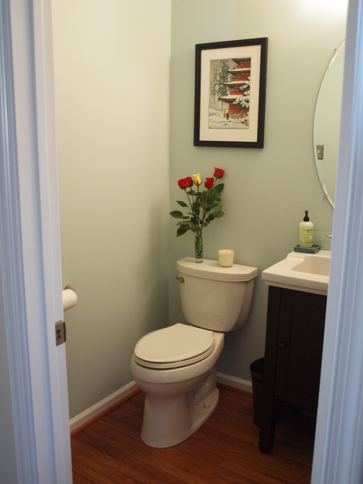 Esempio di un piccolo bagno di servizio classico con lavabo integrato, ante lisce, ante in legno bruno, WC a due pezzi, pareti blu e pavimento in legno massello medio