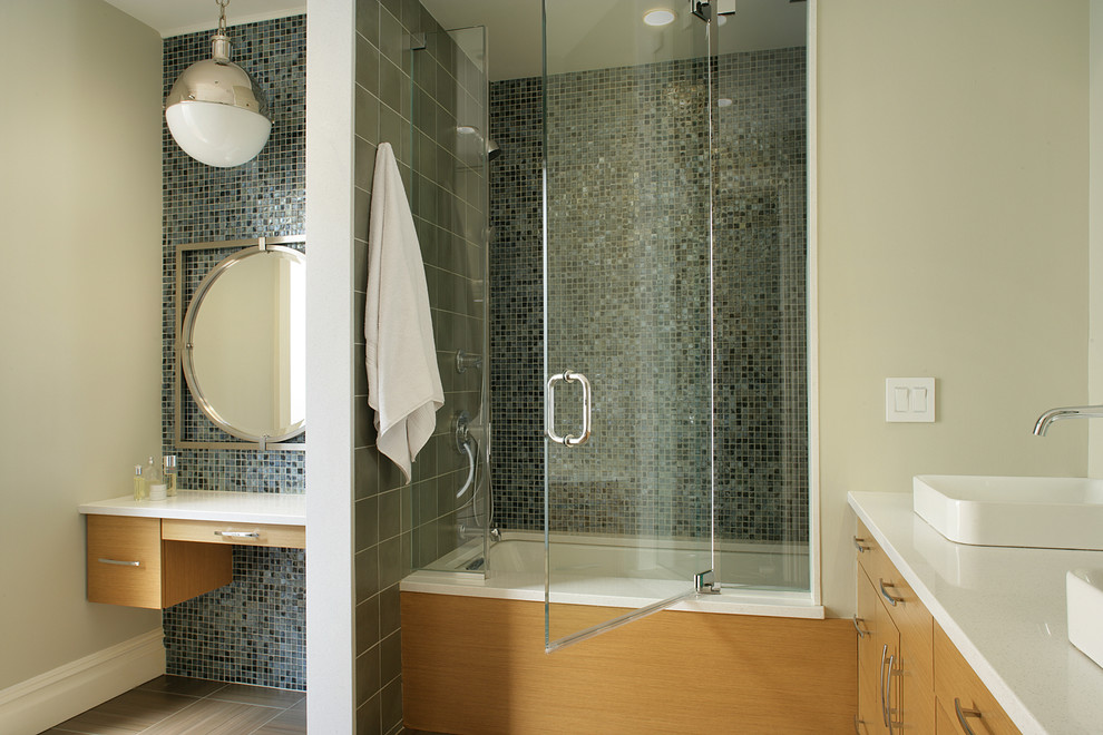 Foto de cuarto de baño contemporáneo con lavabo sobreencimera, armarios con paneles lisos, puertas de armario de madera clara, bañera encastrada sin remate, combinación de ducha y bañera, baldosas y/o azulejos azules y baldosas y/o azulejos en mosaico