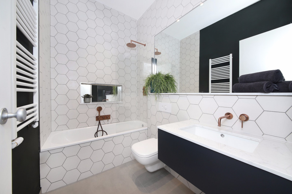Idéer för ett mellanstort modernt vit badrum med dusch, med släta luckor, svarta skåp, ett platsbyggt badkar, en dusch/badkar-kombination, en vägghängd toalettstol, vit kakel, porslinskakel, svarta väggar, ett undermonterad handfat, bänkskiva i akrylsten och grått golv